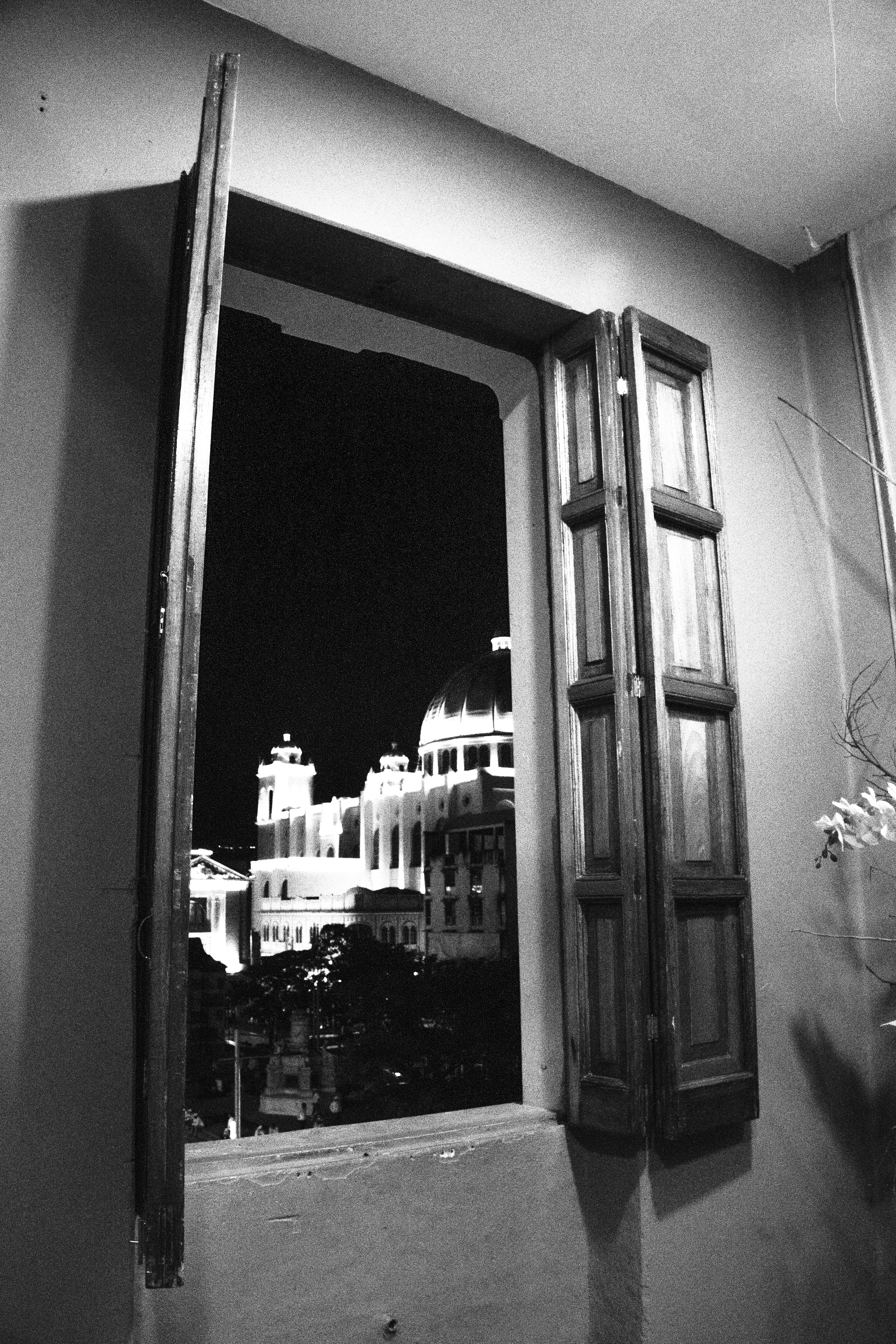 Catedral iluminada de noche vista desde una ventana con contraventanas