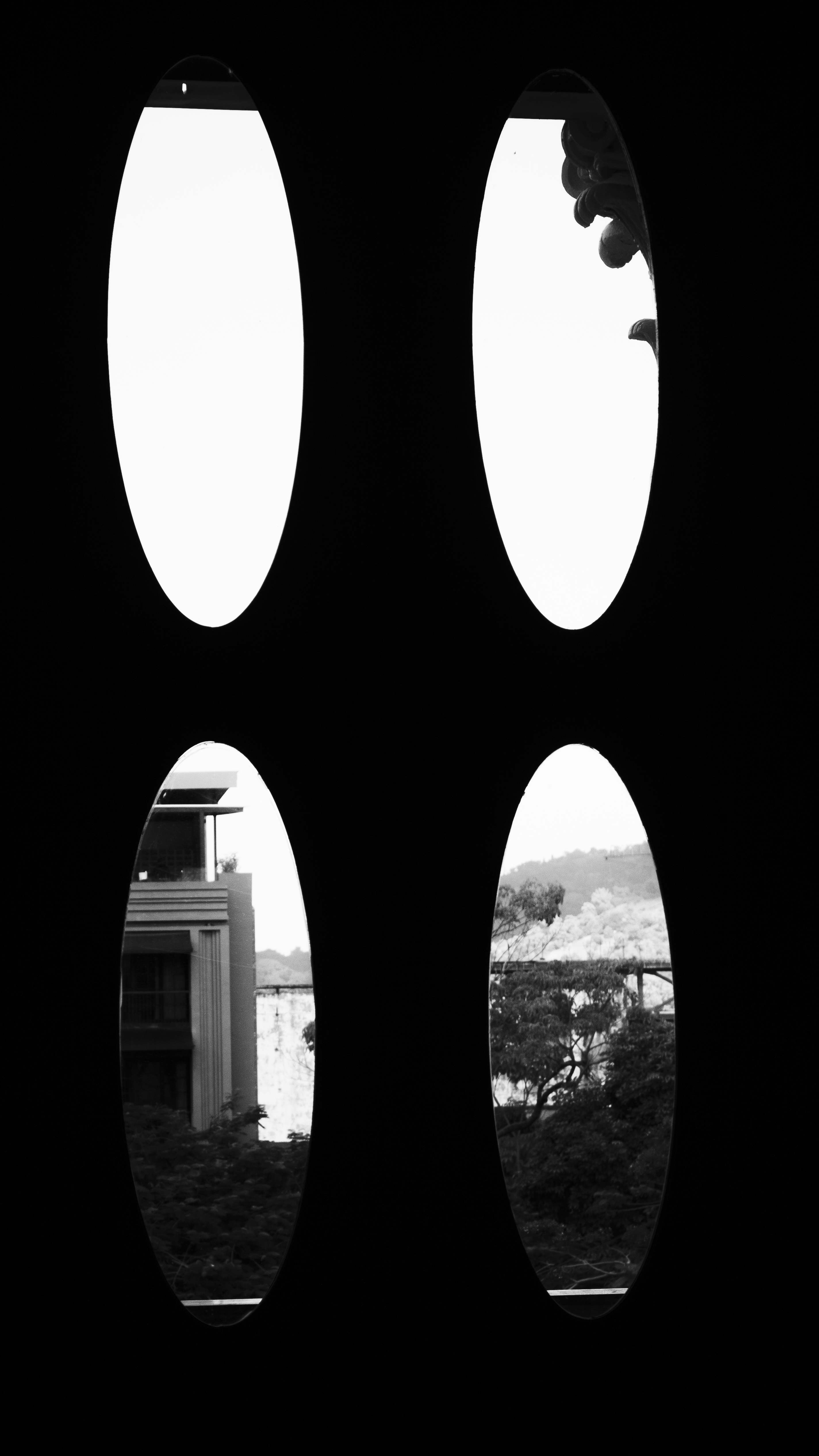 Cuatro óvalos negros enmarcando cielo, arquitectura y paisaje