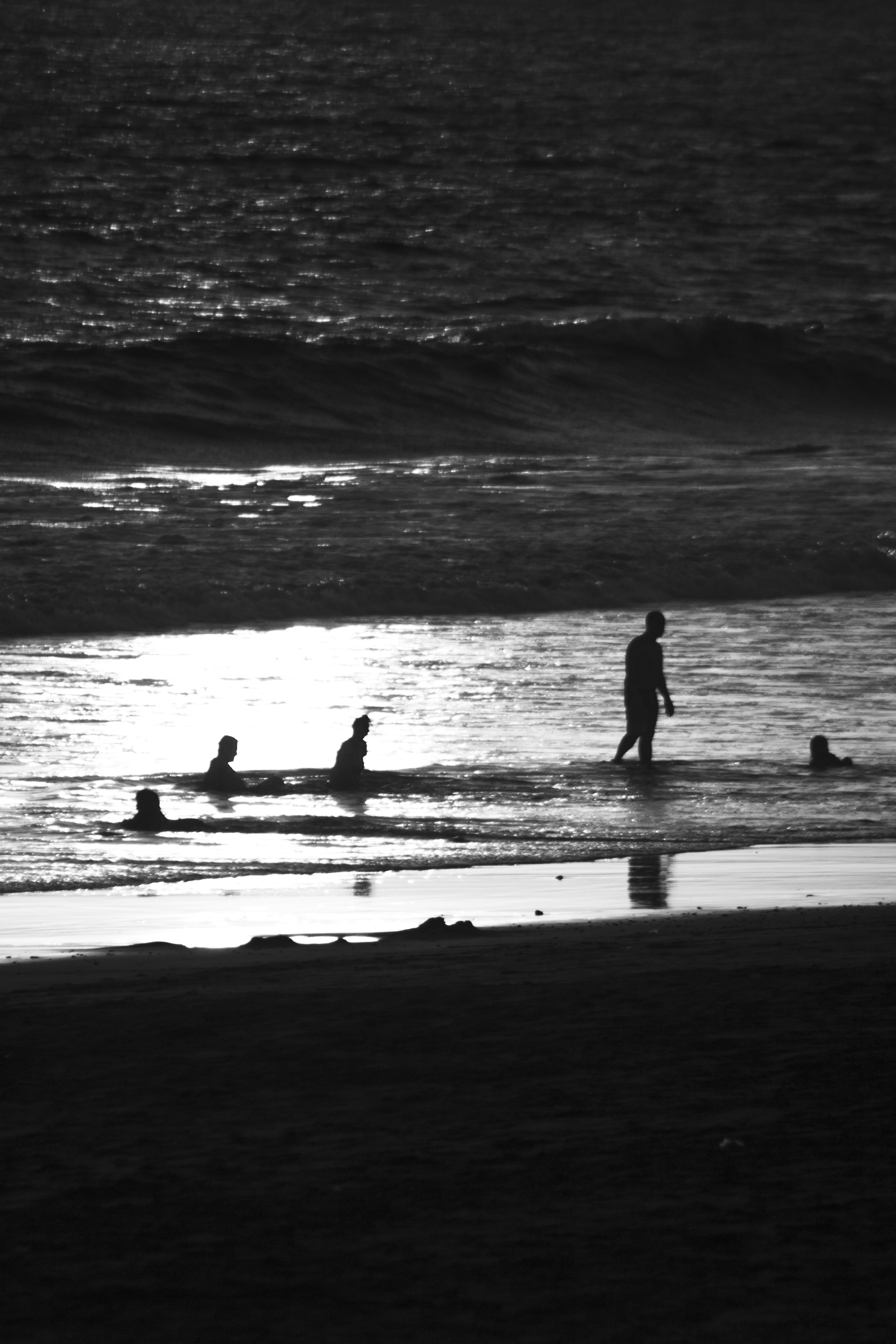 Siluetas en la orilla con reflejo de luz sobre el agua