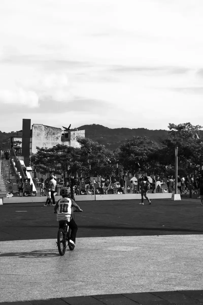 Niño en bicicleta alejándose por una plaza pública