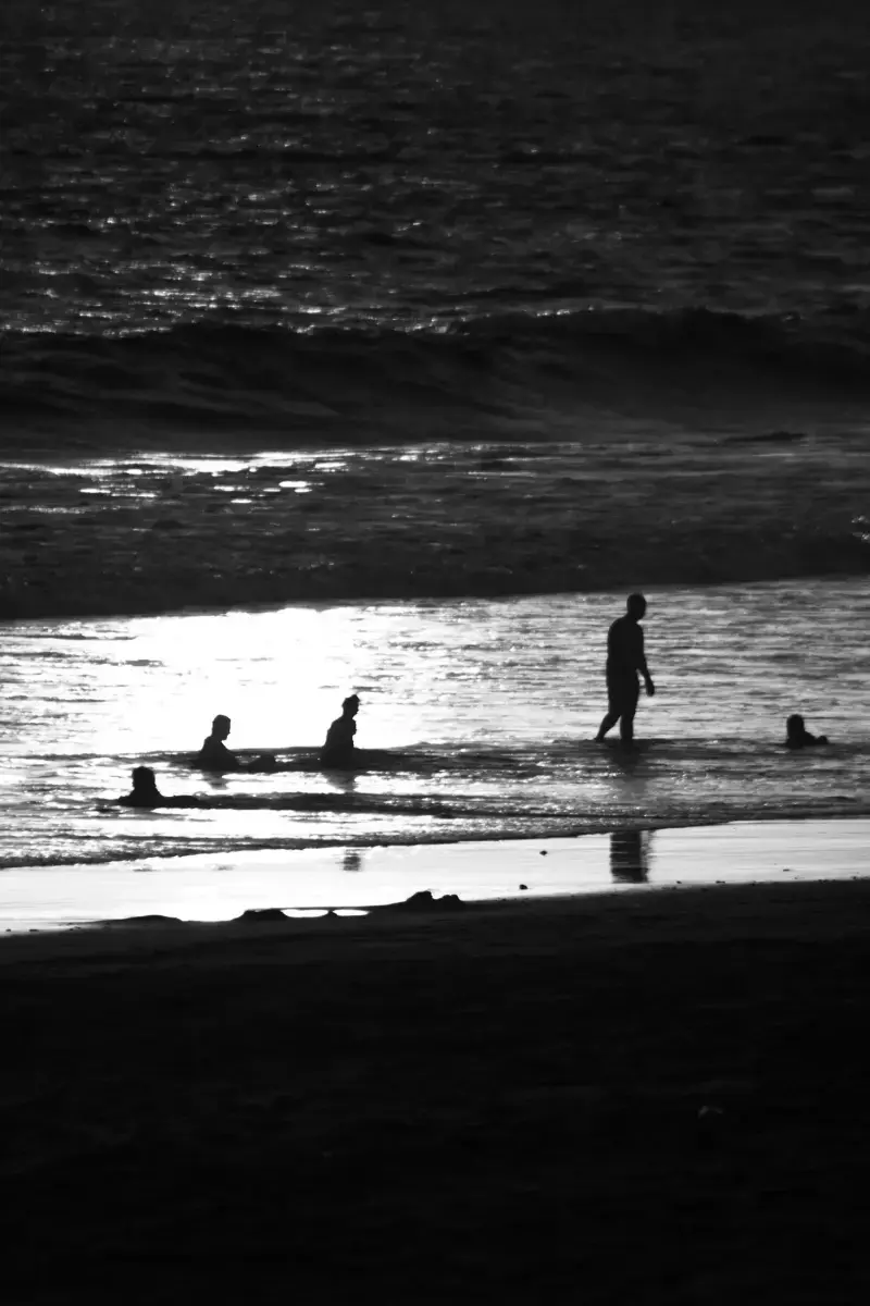 Siluetas en la orilla con reflejo de luz sobre el agua